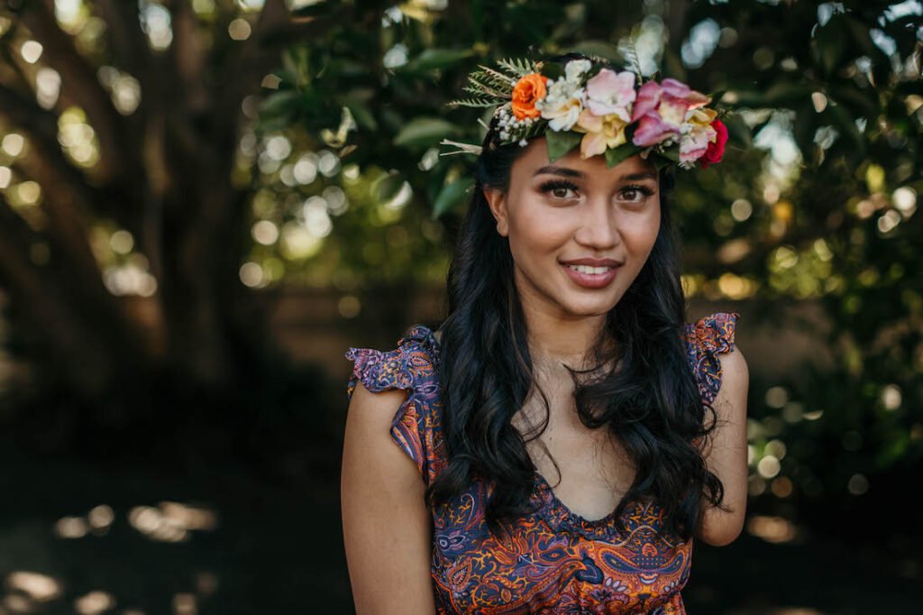 A beautiful portrait of Ellice wearing her haku lei in a grove of trees.