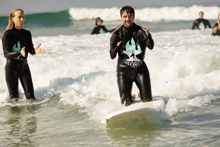Forge attendee Matthew smiles as he catches one of his first waves on surf day.