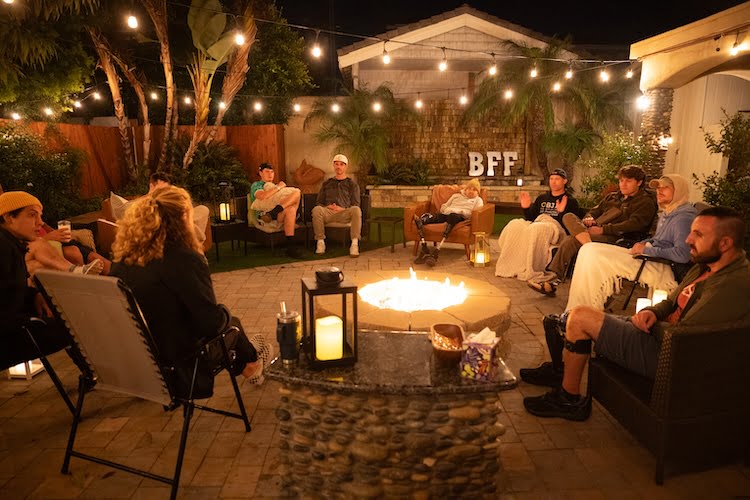 The Forge men sit outside around the fire pit listening to the group session speaker and participating in the discussion.