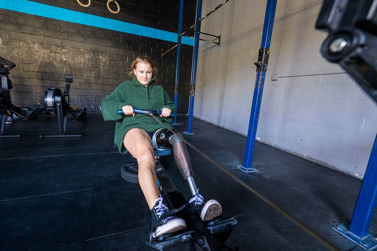 Beautifully Flawed attendee Keely rows on the rowing machine with her left leg prosthetic.