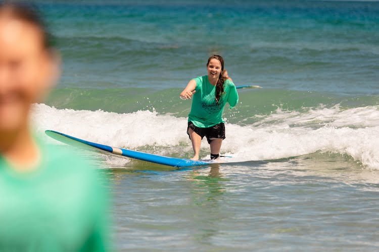 Beautifully Flawed attendee catches a wave while surfing in Kauai.