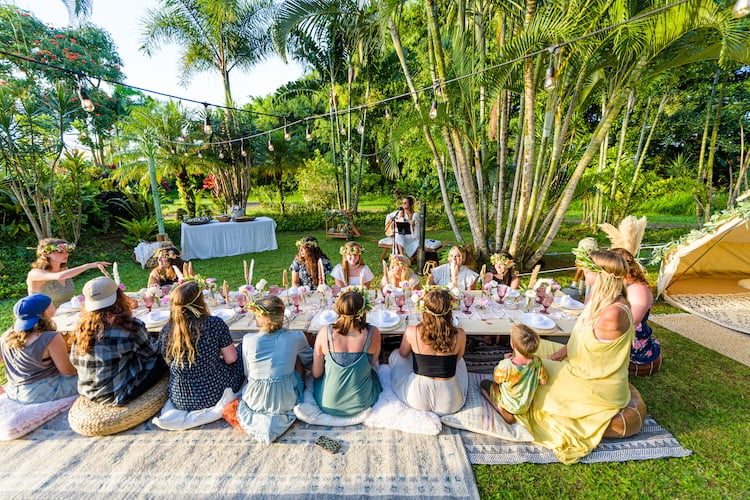 The Beautifully Flawed attendees sit and enjoy a beautiful bohemian picnic in a picturesque Hawaiian landscape.