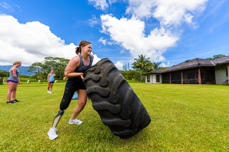 Attendee Kali, a right leg amputee, uses all her strength to flip a huge tire to complete a CrossFit challenge.