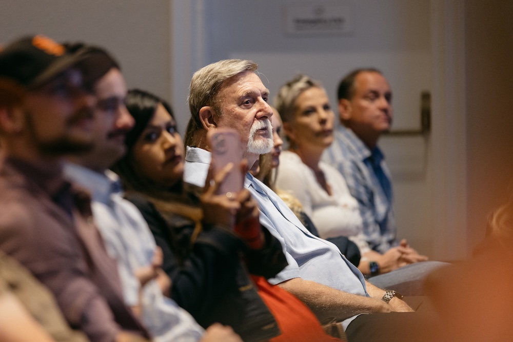 A close-up view of audience members attentively listening during a Shine Forth presentation.