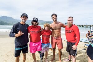Surf instructors and participants pose together on the beach after a surfing session.